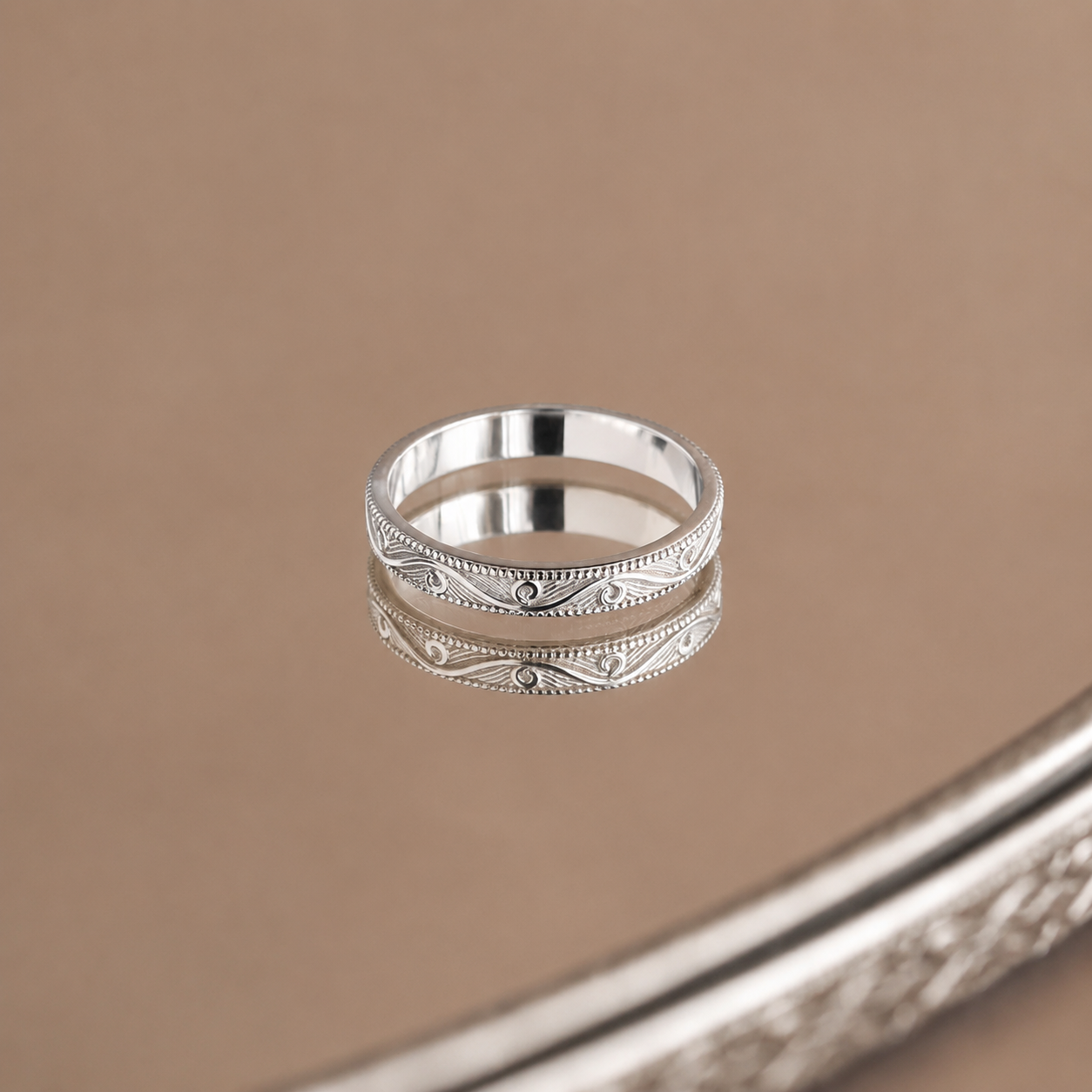 Silver ring with intricate design on a brown background